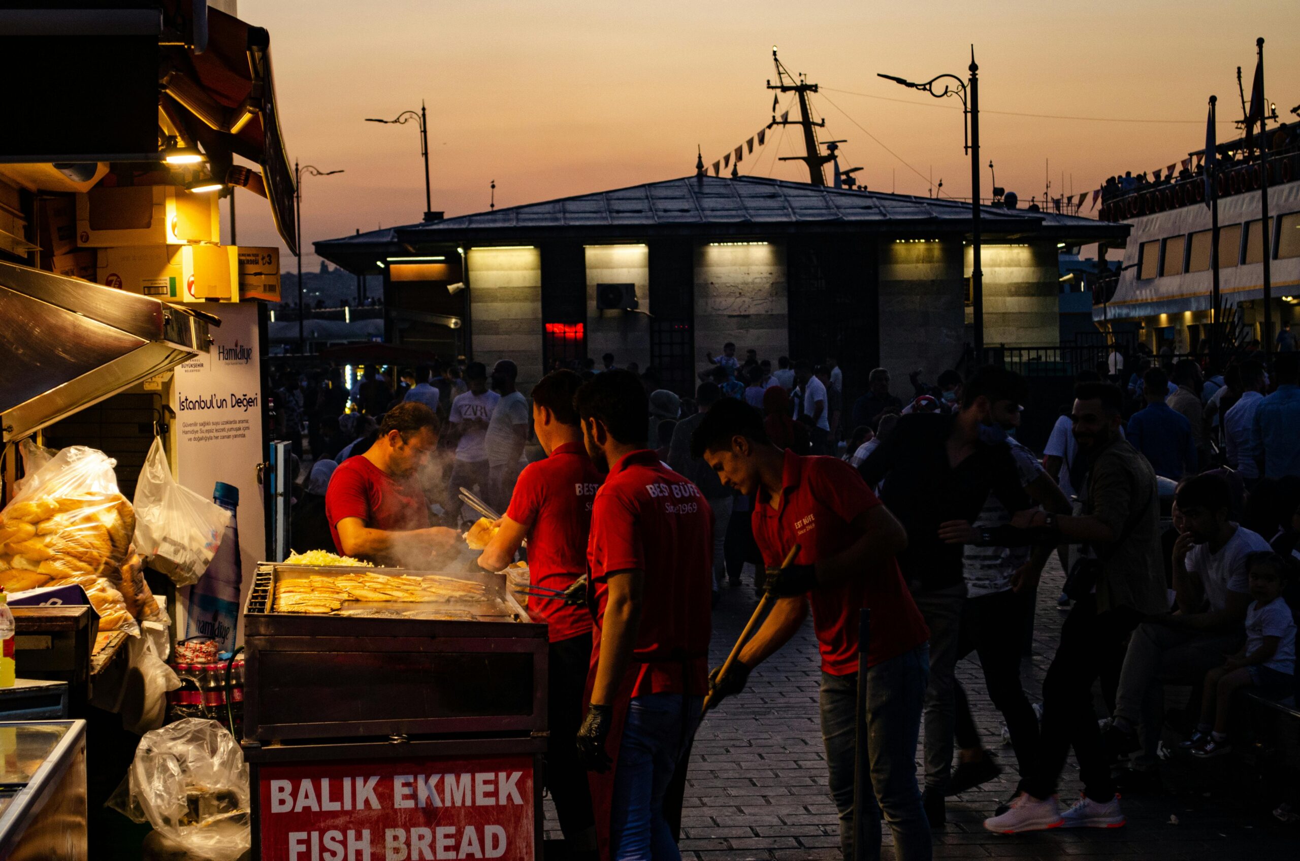 Captivating evening scene of street food vendors grilling Balik Ekmek by the Bosphorus in Istanbul.